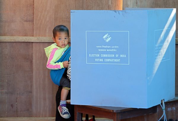 A woman holds her child as she casts her vote at a polling station during state assembly elections in Mizoram, India, 28 November 2018 (Photo: Reuters/Jayanta Dey).