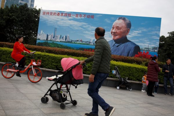 People walk past a poster of late Chinese leader Deng Xiaoping, who launched the country on its reform and opening program, in Shenzhen, Guangdong Province, China, 13 December 2018. (Photo: Reuters/Thomas Peter).