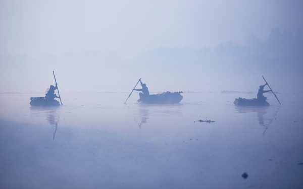 Men paddle their handmade boats across the Yamuna river on a foggy winter morning in New Delhi, India, 27 December 2018 (Photo: Reuters/Adnan Abidi).