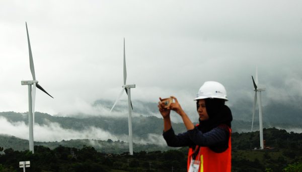 A woman takes pictures of wind power plant propeller blades in Sidenreng Rappang, Sulawesi Island of Indonesia, 15 January 2018 (Photo: Antara Foto/Yusran Uccang via Reuters).