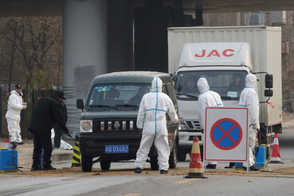 Workers in protective suits are seen at a checkpoint on a road leading to a village near a farm where African swine fever was detected, in Fangshan district of Beijing, China, 23 November 2018 (Photo: Reuters/Stringer).