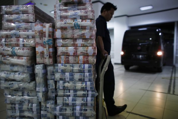 Vendor waits to load Indonesian rupiah banknotes into a vehicle, Jakarta, 18 November 2014 (Photo: Reuters/Darren Whiteside).