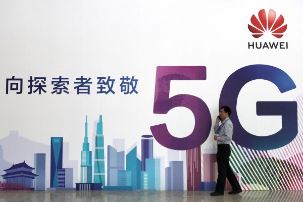 A man talks on his phone beside a Huawei's billboard featuring 5G technology at the PT Expo in Beijing, China, 26 September 2018 (Photo: Reuters/Stringer).