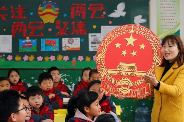 A teacher gives a lesson on the Chinese National People's Congress (NPC) and People's Political Consultative Conference (CPPCC) with a cutout of a Chinese national emblem at a primary school in Weinan, Shaanxi province, China, 4 March 2019. (Photo: Reuters/Stringer)