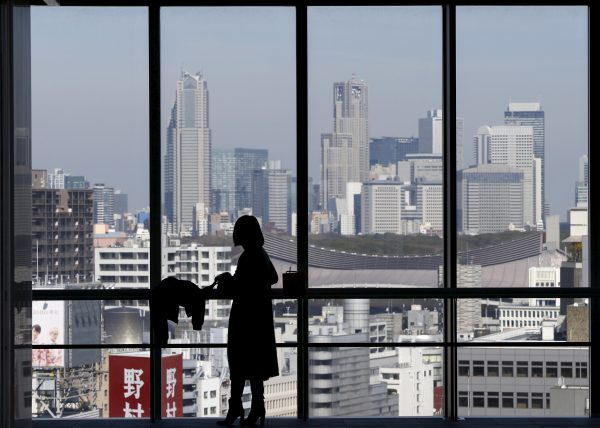 A woman silhouetted against a window overlooking skyscrapers at Shinjuku district, Tokyo, Japan (Photo: Reuters/Issei Kato).