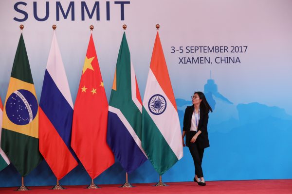 A staff worker walks past the national flags of Brazil, Russia, China, South Africa and India before a group photo during the BRICS Summit at the Xiamen International Conference and Exhibition Center in Xiamen, China, 4 September 2017 (Photo: Reuters/Wu Hong/Pool).
