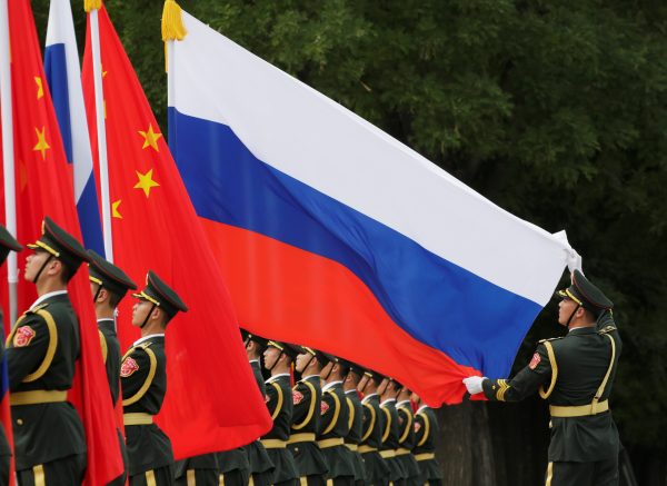 A military officer adjusts a Russian flag ahead of a welcome ceremony hosted by Chinese President Xi Jinping for Russian President Vladimir Putin outside the Great Hall of the People in Beijing, China, 8 June 2018 (Photo: Reuters/Jason Lee).