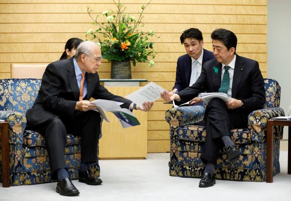 Angel Gurria (L), Secretary-General of the OECD shows reports about the G20 to Japanese Prime Minister Shinzo Abe (R) in Tokyo, Japan, 15 April 2019 (Photo: Kimimasa Mayama/Pool via REUTERS).