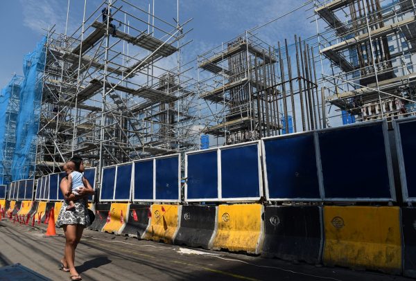 A woman carrying a baby passes though a construction of the Metro Rail Transit on Commonwealth Avenue in Quezon City, metro Manila, 23 May 2018 (Photo: Reuters/Dondi Tawatao).