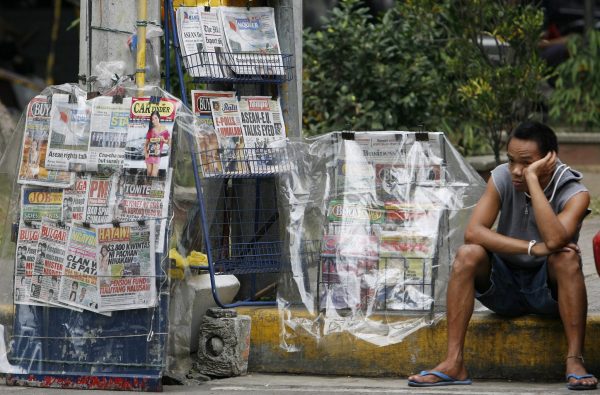A newspaper vendor waits for customers along a street in Manila (Photo: Reuters/Romeo Ranoco).