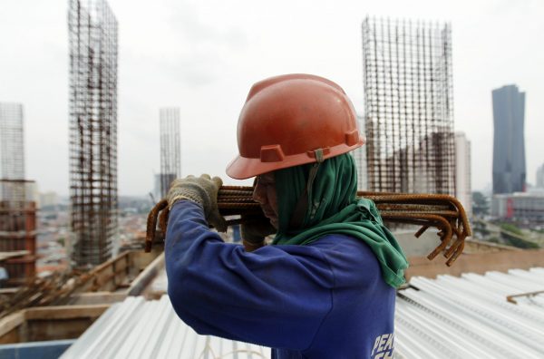 A worker carries steel rods as he walks on the 18th floor of 