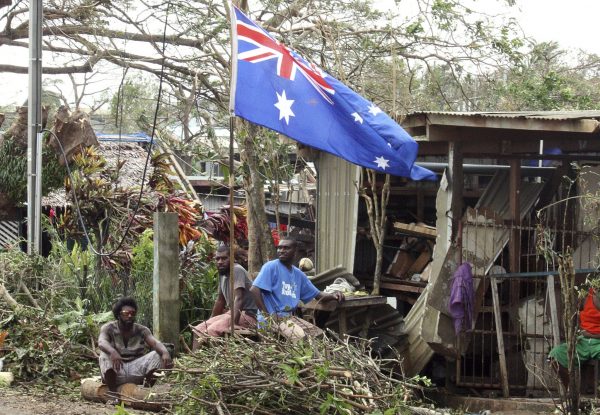 Local residents sit outside their damaged homes surrounded by debris on a street after Cyclone Pam hit Port Vila, Vanuatu, 15 March 2015. (Photo: Reuters/Kris Paras)