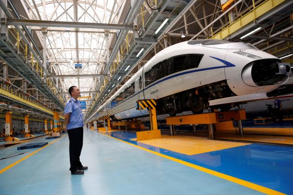 A worker stands next to a high-speed train at the maintenance and repair depot of China Railway High-speed (CRH) rail service during a media tour in Beijing, China, 30 August 2018. (Photo: Reuters/Thomas Peter).
