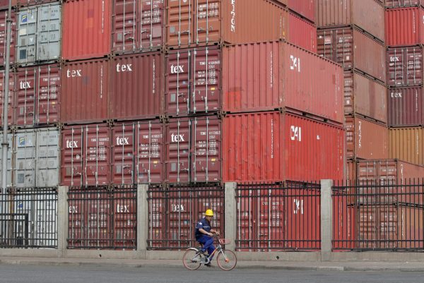 A worker cycles past containers outside a logistics center near Tianjin Port, China, 16 May 2019 (Photo: Reuters/Jason Lee).