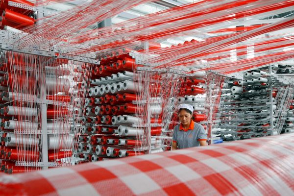 A woman works at a workshop manufacturing plastic woven materials for packaging products in Suqian, Jiangsu province, China, 13 July 2019. (Photo: Reuters/Stringer).