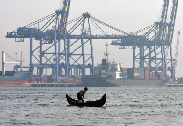 A fisherman prepares to cast his fishing net in the waters of the Vembanad lake as a container ship is seen docked at a port in Vallarpadam, Kochi, India (Photo: Reuters/Sivaram V).
