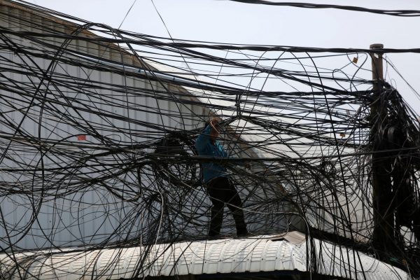 An electrician prepares electrical wires along a street in Phnom Penh, Cambodia, 23 April 2018 (Photo: Reuters/Samrang Pring).