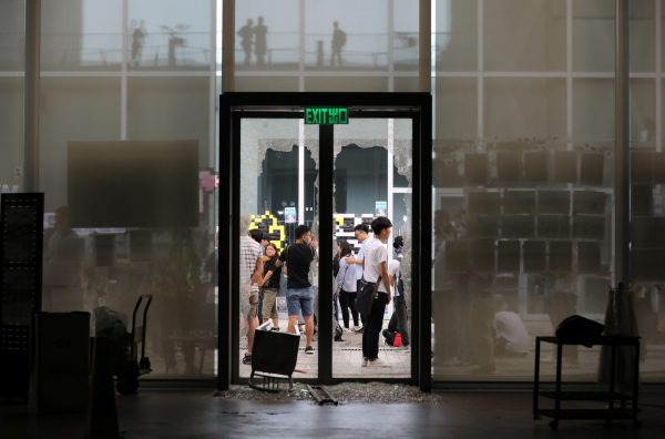 People stand in front of the smashed glass door of Hong Kong Design Institute during a demonstration in Tiu Keng Leng in Hong Kong, 17 October 2019. (Photo: REUTERS/Ammar Awad).