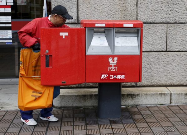 A worker of Japan Post Co, which has faced controversy for its different treatment of workers, collects postal items from a post box outside a post office in Tokyo, Japan, 2 November 2015 (Photo: Reuters/Toru Hanai).