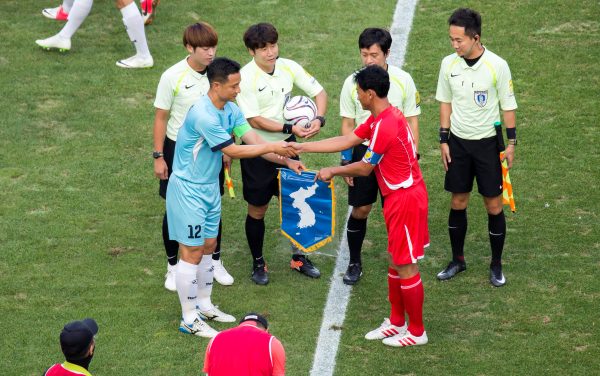 Je Yong-Sam (front L), captain of a South Korean workers' soccer team gives a Korean unification flag to Kang Jin-Hyuk, captain of a North Korean workers' soccer team before their inter-Korean friendly soccer match at the Seoul World Cup Stadium in Seoul, South Korea, 11 Aug 2018 (Photo: Reuters/Lee Jae-Won).