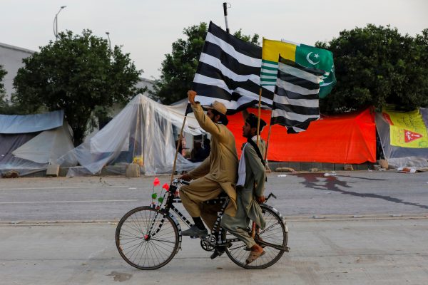 Supporters of religious and political party Jamiat Ulema-i-Islam-Fazal (JUI-F) chant slogans as they ride on a bike with flags of the party and Azad Kashmir, during the so called Azadi March (Freedom March), called by the opposition to protest against the government of Prime Minister Imran Khan in Islamabad, Pakistan 11 November 2019. (Photo:Reuters/Akhtar Soomro).