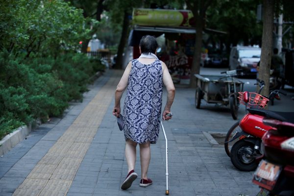 An elderly woman walks with a stick along a street in downtown Beijing, China 30 July, 2019 (Photo: Reuters/Lee).