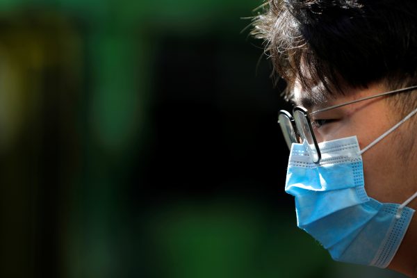 A person wearing a face mask stands on Swanston Street after cases of the coronavirus were confirmed in Melbourne, Victoria, Australia, 29 January, 2020 (Photo: Reuters/Kelly).