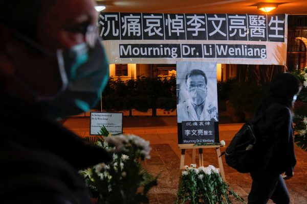 People wearing masks attend a vigil for the late Dr Li Wenliang, an ophthalmologist who died of coronavirus at a hospital in Wuhan, China, 7 February 2020 (Photo: Reuters/Tyrone Siu).
