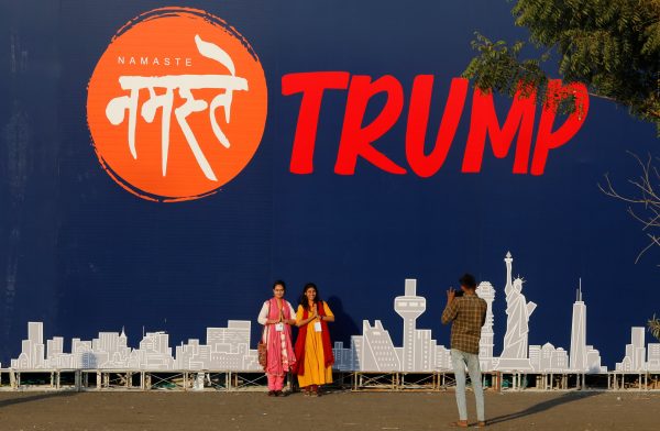 People pose for a picture in front of a hoarding of the 'Namaste Trump' event ahead of US President Donald Trump's visit in Ahmedabad, India, 22 February 2020 (Photo: REUTERS/Anushree Fadnavis).