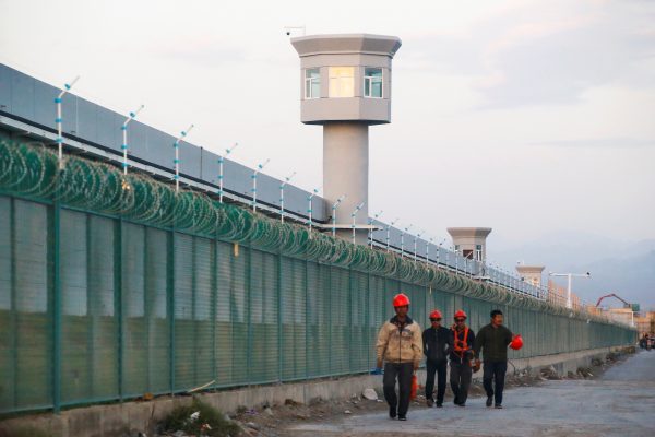 Workers walk by the perimeter fence of what is officially known as a vocational skills education centre in Dabancheng, Xinjiang Uyghur Autonomous Region, China, 4 September 2018 (Photo: Reuters/Thomas Peter).