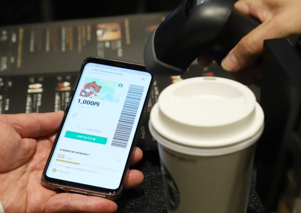 Starbucks Coffee Japan employee demonstrates cashless payment with Japan’s SNS giant LINE’s account on a mobile phone, Tokyo, Japan, 8 April 2019 (Photo: Reuters/Yoshio Tsunoda).