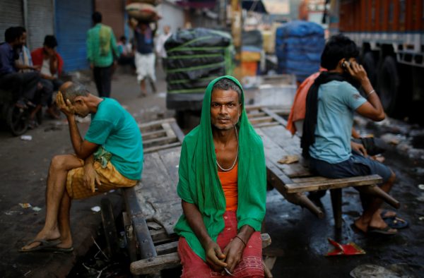 Migrant labourers sit on a handcart as they wait for work at a wholesale market in the old quarters of Delhi, India, 10 October, 2019 (Photo: Reuters/Siddiqui).