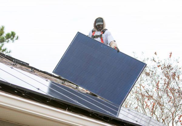 Terell Odom, of Compass Solar Energy, moves a solar panel into place on a house in Milton, 11 Dec 2019 (Photo: Reuters).