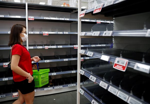 A woman wearing a protective mask passes empty shelves of instant noodles and canned food, as people initially stocked up on food supplies after Singapore raised coronavirus outbreak alert level to orange, at a supermarket in Singapore, 8 February 2020 (Reuters/Edgar Su).