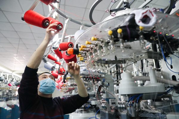 An employee wearing a face mask works on a production line manufacturing socks for export at a factory in Huzhou's Deqing county, Zhejiang province, China 19 February, 2020 (China Daily via Reuters).