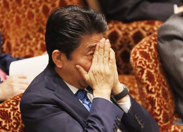 Japanese Prime Minister Shinzo Abe covers his face with his hands as he lisyens to a question by an opposition lawmaker at the National Diet in Tokyo, 3 March 2020 (Photo: Reuters/Yoshio Tsunoda/AFLO).