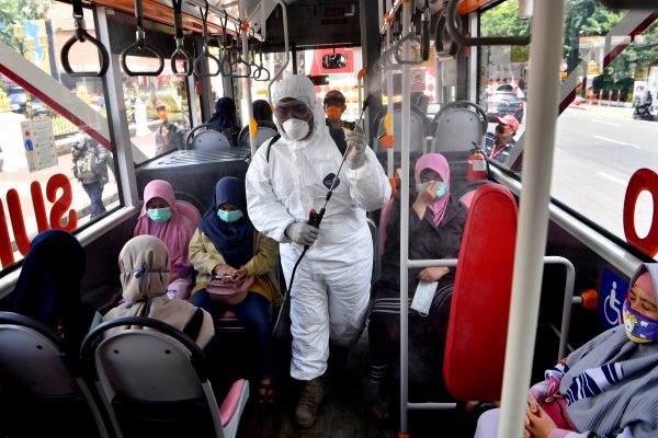 A worker sprays disinfectant in the bus, to prevent the spread of coronavirus disease (COVID-19) in Surabaya, East Java Province, Indonesia, 22 March 2020 (Photo: Antara Foto/Zabur Karuru via REUTERS).
