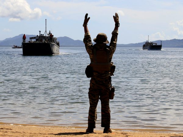 A Filipino soldier displays a hand signal to the landing ships before it docks at Motiong beach, as part of the Humanitarian Assistance and Disaster Response scenario during the Philippines and United States annual Balikatan (Shoulder-to-Shoulder) exercises in Casiguran, Philippines, 15 May 2017 (Photo: REUTERS/Romeo Ranoco).