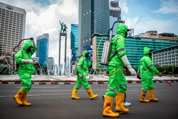 Workers walk in protective suits during an operation of spraying disinfectant to prevent the spread of coronavirus disease in Jakarta, Indonesia 22 March, 2020 (Photo: Reuters/Antara Foto).