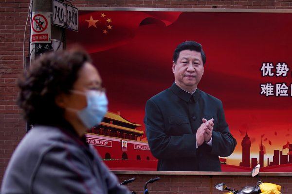A woman wearing a protective mask is seen past a portrait of Chinese President Xi Jinping on a street as the country is hit by an outbreak of the coronavirus, in Shanghai, China, 12 March 2020 (Photo: Reuters/Aly Song).