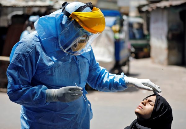A doctor wearing a protective gear prepares to take a swab from a girl to test for the coronavirus disease (COVID-19) at a residential area in Ahmedabad, India, 8 April, 2020 (Photo: Reuters/Dave).