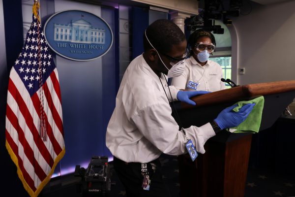 Workers disinfect the podium before the start of US President Donald Trump's daily coronavirus disease (COVID-19) outbreak task force briefing at the White House in Washington DC, 9 April 2020 (Photo: REUTERS/Jonathan Ernst).