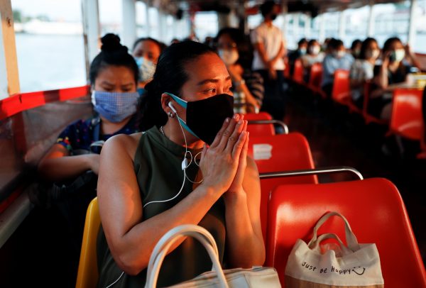 A woman prays as she passes a temple while commuting by boat, at the Chao Phraya river during the coronavirus disease (COVID-19) outbreak, in Bangkok, Thailand, 15 April, 2020 (Photo: Reuters/Jorge Silva).