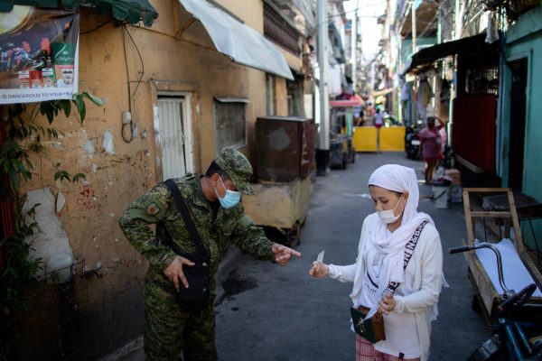 A soldier wearing a protective mask checks a woman's quarantine pass as the city undergoes a stricter lockdown to contain the coronavirus disease (COVID-19) spread, in Pasay City, Philippines, 22 April 2020 (Photo: Reuters/Eloisa Lopez).