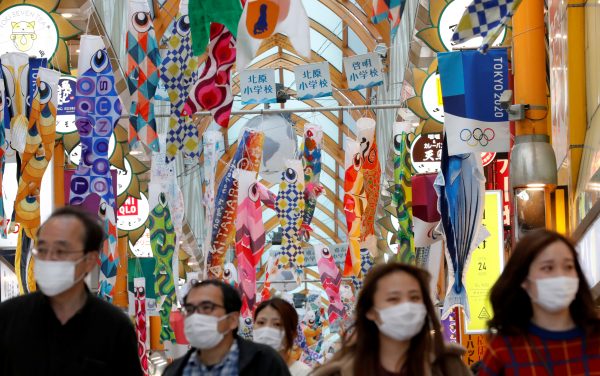 People wearing face masks walk under fluttering Koinobori, traditional Japanese carp-shaped windsocks that are hung in Japan from April to early May to wish a good health for children, following the coronavirus disease (COVID-19) outbreak, in Tokyo, Japan, 24 April, 2020. (Photo: Reuters/Kim Kyung-Hoon).