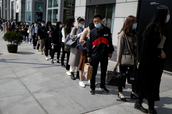 People wearing face masks, following the coronavirus disease (COVID-19) outbreak, make a line to enter an office building in Beijing, China is 28 April, 2020 (Photo: Reuters/Carlos Garcia Rawlins).