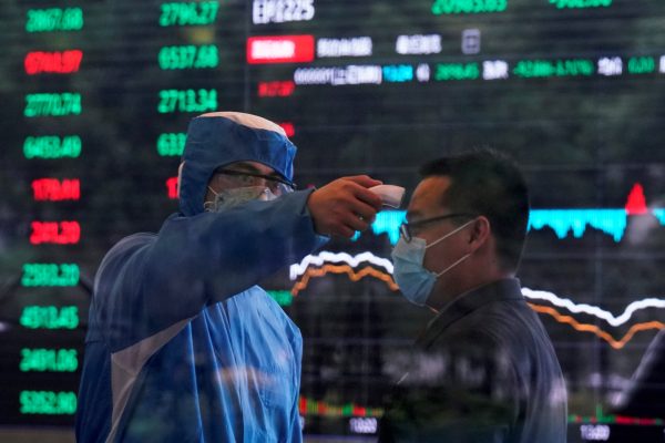 A worker wearing a protective suit takes body temperature measurement of a man inside the Shanghai Stock Exchange building, as the country is hit by a new coronavirus outbreak, at the Pudong financial district in Shanghai, China 28 February 2020 (Reuters/Aly Song).