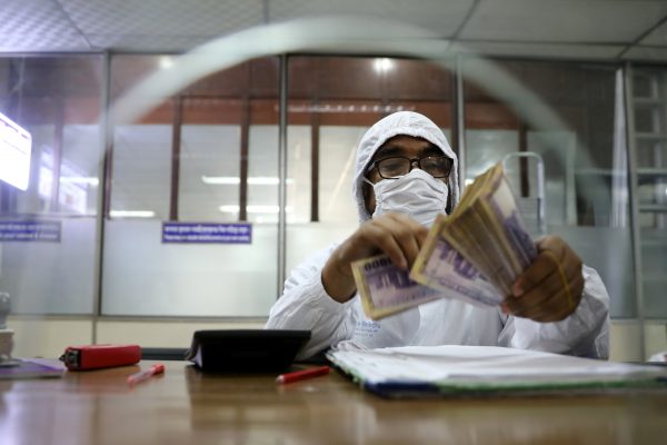 A government bank employee wears a protective suit while counting money amid the coronavirus disease (COVID-19) outbreak in Dhaka, Bangladesh, 2 April 2020 (Photo: REUTERS/Mohammad Ponir Hossain).