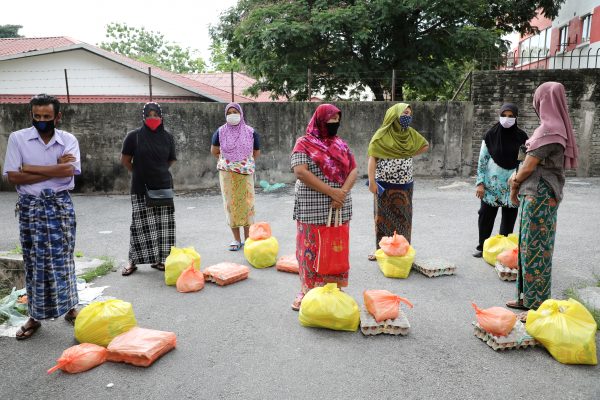 Rohingya refugees wearing protective masks keep a social distance while waiting to receive goods from volunteers, during the movement control order due to the outbreak of the coronavirus disease (COVID-19), in Kuala Lumpur, Malaysia 7 April, 2020 (Photo: Reuters/Lim Huey Teng).