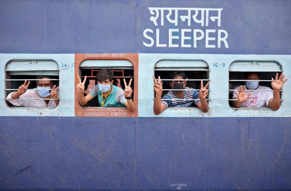 Migrant workers and pilgrims, who were stranded in the western state of Rajasthan due to a lockdown imposed by the government to prevent the spread of coronavirus disease (COVID-19), gesture from inside a train upon their arrival in their home state of eastern West Bengal, at a railway station on the outskirts of Kolkata, India, 5 May, 2020 (Photo: Reuters/Rupak De Chowdhuri).